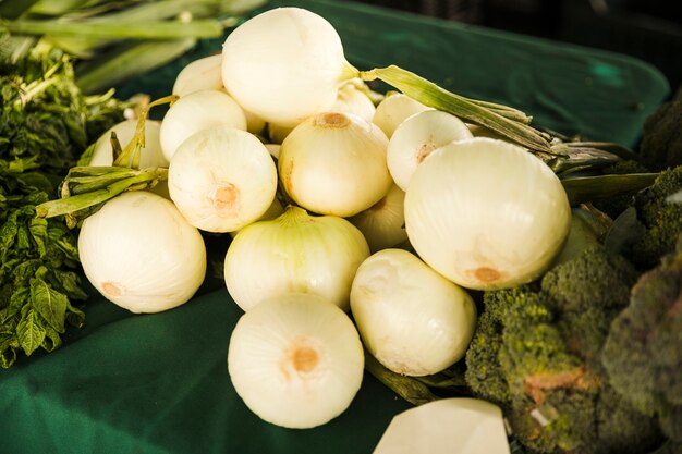 Gesunde weiße Zwiebel mit grünem Gemüse auf Tabelle am Markt