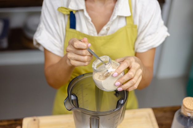 Gesunder Frühstück Chia Pudding Herstellungsprozess. Frau mischen Chiasamen, Mandelmilch und natürliche Farbe Drachenfruchtrosa-Extrakt im Mixer.