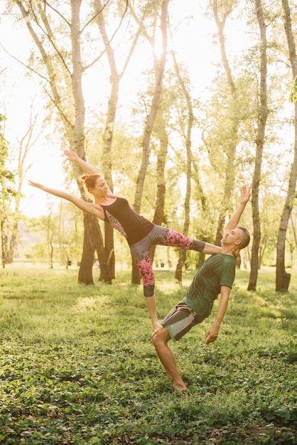 Gesunder Mann und Frau, die acroyoga im Park tut