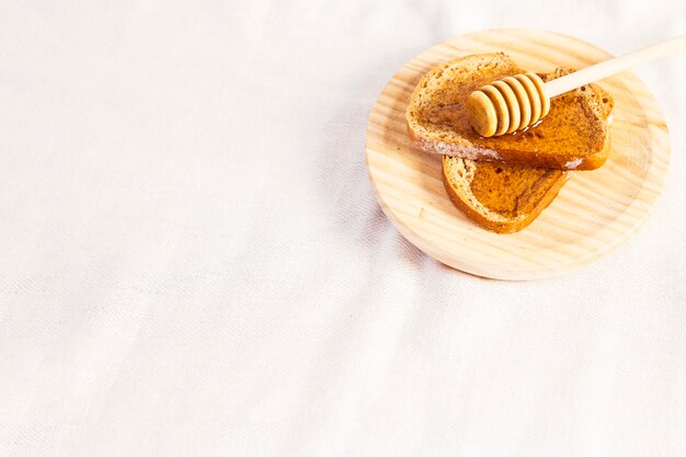 Gesunder natürlicher Honig und Brot in der Platte über weißem Stoff