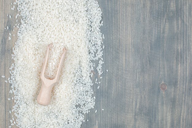 Gesunder roher Reis mit Holzlöffel auf einem Holztisch