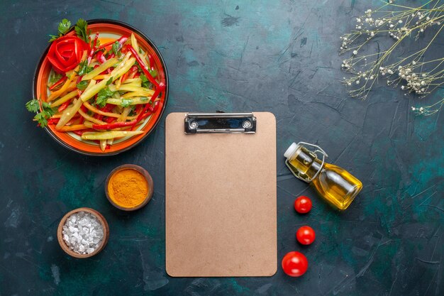 Gesunder Salat der geschnittenen Paprika der Draufsicht mit Gewürzen und Olivenöl auf blauem Hintergrund