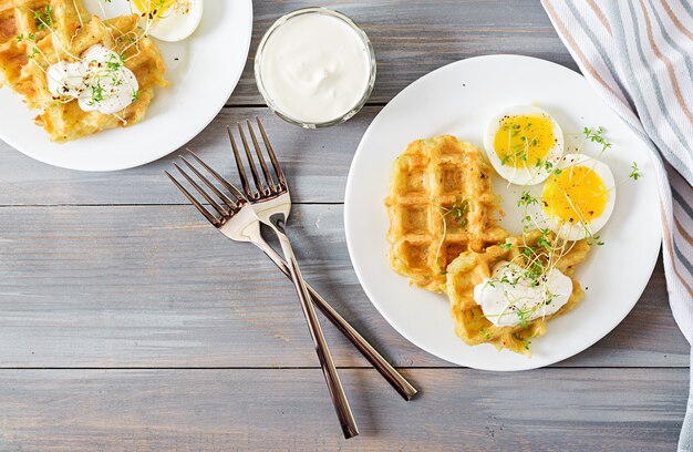 Gesundes Frühstück oder Snack. Kartoffelwaffeln und gekochtes Ei auf grauem Holztisch. Ansicht von oben. Flach liegen