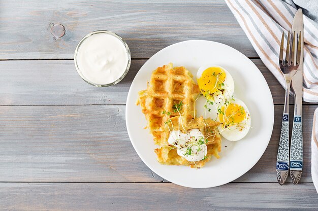 Gesundes Frühstück oder Snack. Kartoffelwaffeln und gekochtes Ei auf grauem Holztisch. Ansicht von oben. Flach liegen