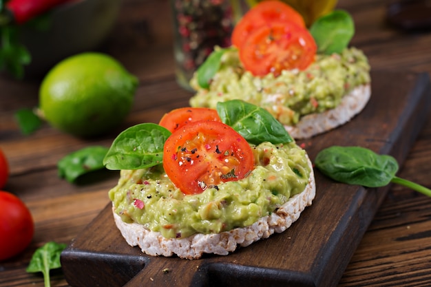 Gesundes Frühstück. Sandwich Knäckebrot mit Guacamole und Tomaten auf einem Holztisch.