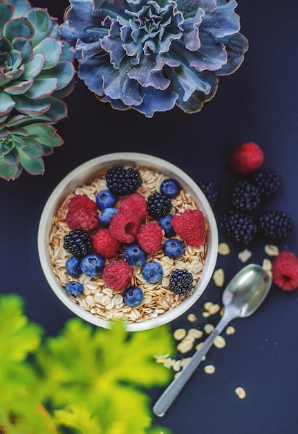 Gesundes Frühstück. Weißer Teller mit Haferflocken und verschiedenen Beeren auf blauem Hintergrund. Sommerernte.