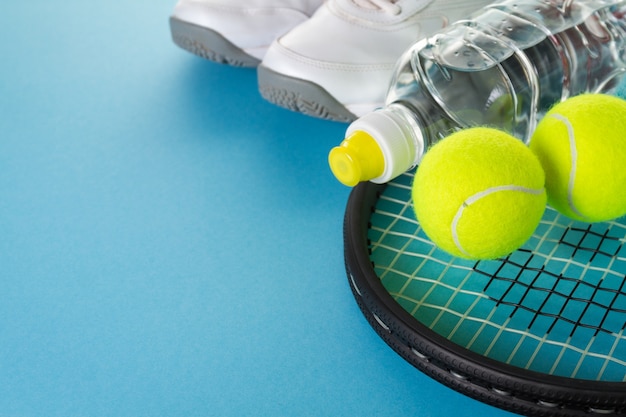 Gesundes Leben Sport Konzept. Sneakers mit Tennisbällen, Handtuch und Flasche Wasser auf hellem blauem Hintergrund. Text kopieren