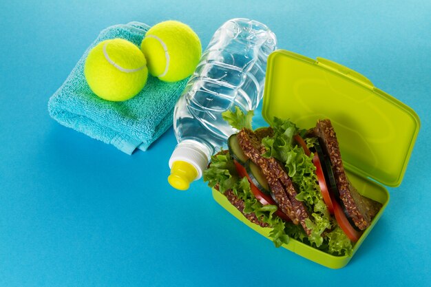 Gesundes Leben Sport Konzept. Sneakers mit Tennisbällen, Handtuch und Flasche Wasser auf hellem gelben Hintergrund. Text kopieren