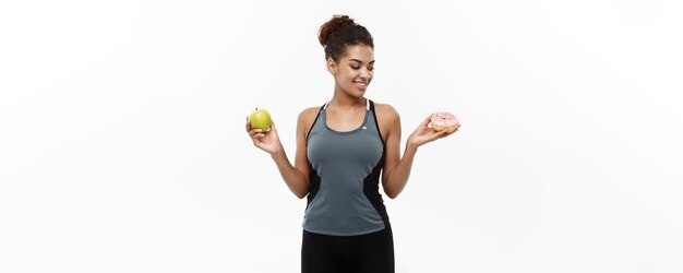 Gesundes und ernährungskonzept schöne sportliche afroamerikaner treffen eine entscheidung zwischen donut und grün