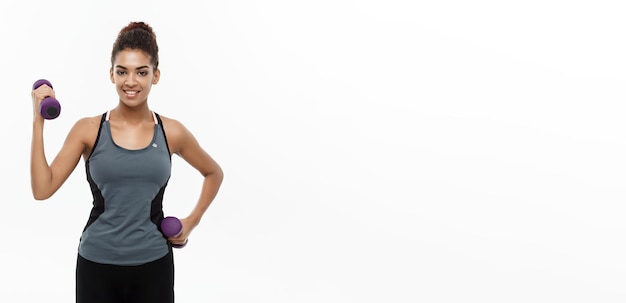 Kostenloses Foto gesundes und fitnesskonzept schöne amerikanische afrikanerin im fitnesskleidungstraining mit hantel