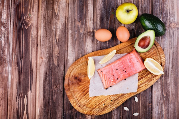 Gesundes und frisches Essen. Roher Lachs mit Zitronen, Eiern, Äpfeln, Avocado und Messern