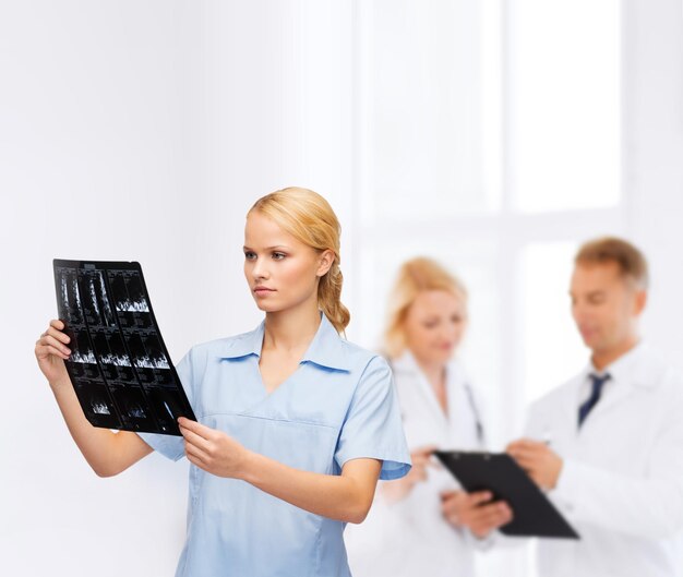Gesundheits-, medizin- und radiologiekonzept - lächelnder arzt oder krankenschwester, der röntgenstrahlen betrachtet
