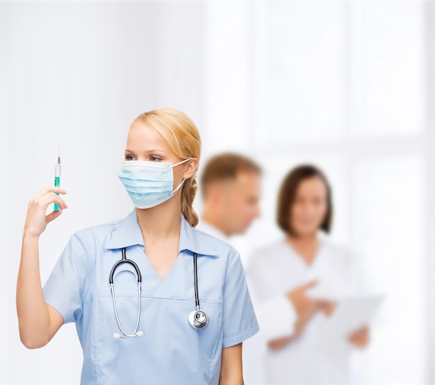 Gesundheits- und medizinisches konzept - ärztin oder krankenschwester in medizinischer maske, die spritze mit injektion hält