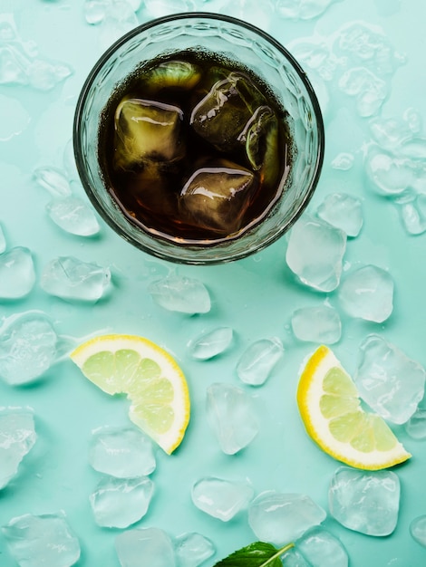 Getränk im Glas nahe Zitronen und Eisblöcken