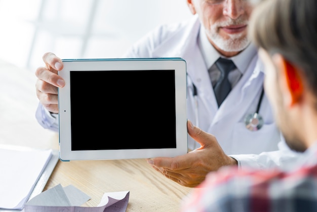 Getreidearzt, der dem Patienten Tablette zeigt