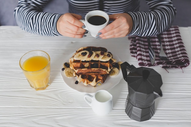 Getreidefrau, die mit Waffeln und Kaffee frühstückt