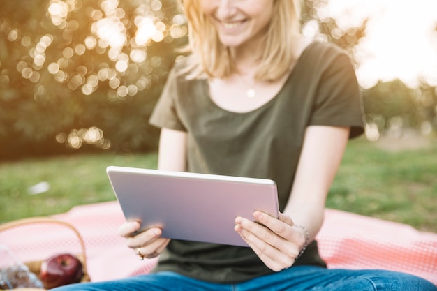 Getreidefrau, die Tablette am sonnigen Tag verwendet