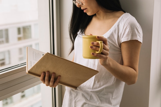 Getreidefrau mit dem Becher, der nahe Fenster liest