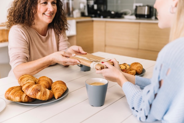 Kostenloses Foto getreidetochter, die der mutter geschenk während des frühstücks gibt