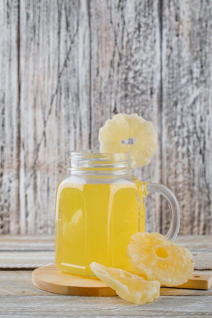 Getrocknete Ananas mit Saft auf Holz- und Schneidebrettoberfläche