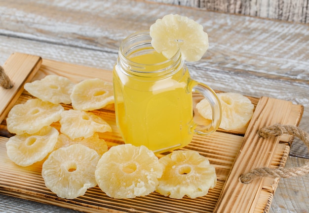 Getrocknete Ananas mit Saft in einem Tablett auf Holzoberfläche