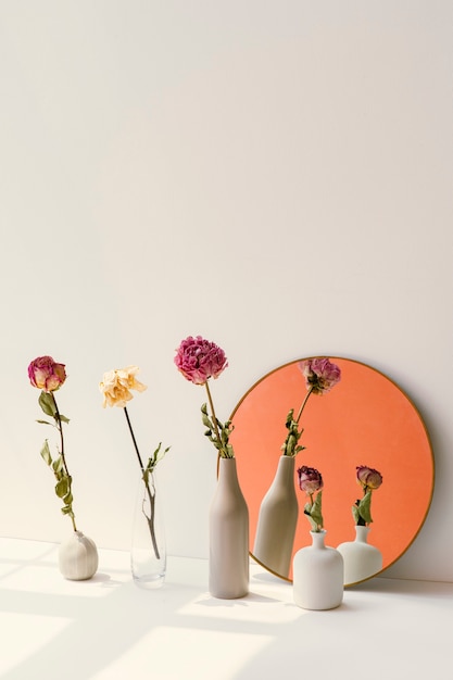 Getrocknete Blumen in minimalen Vasen von einem runden Spiegel