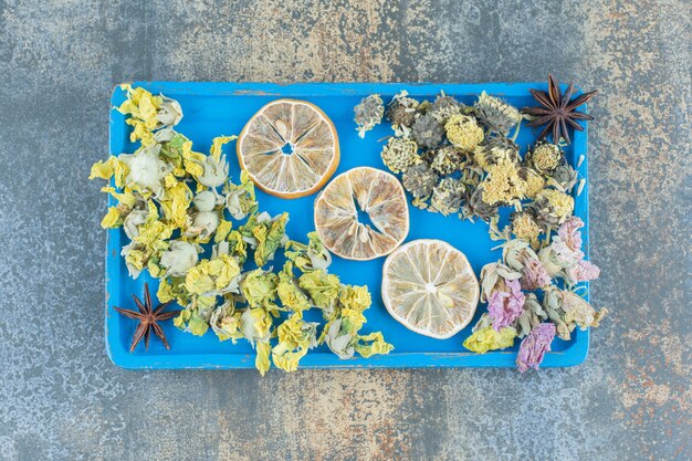 Getrocknete Blumen und Zitronenscheiben auf blauem Teller.