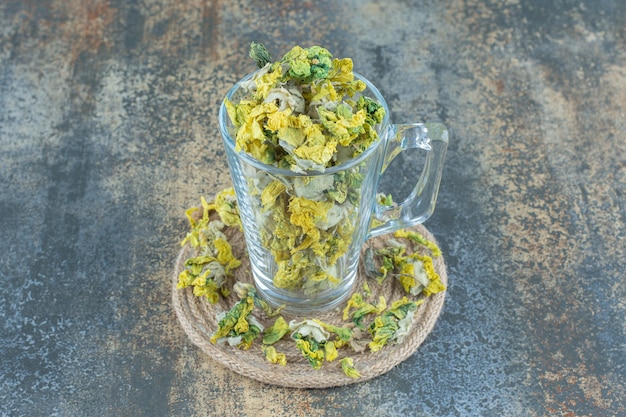 Getrocknete chrysanthemenblüten im glas auf blau.