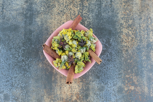 Getrocknete Chrysanthemenblüten und Zimt in rosa Schüssel.