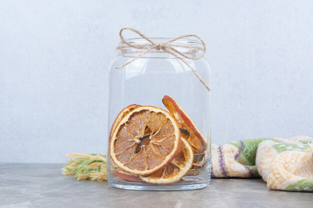 Getrocknete Orangenscheiben im Glas auf Steintisch.