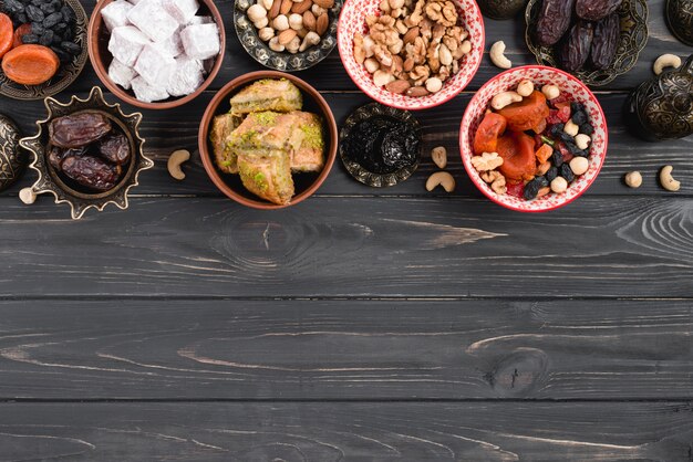 Getrocknete rohe Bio-Datteln; getrocknete Früchte; Nüsse; Lukum und Baklava auf schwarzem Holztisch