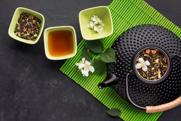 Getrocknetes Teekraut mit weißer Jasminblume auf strukturiertem Hintergrund