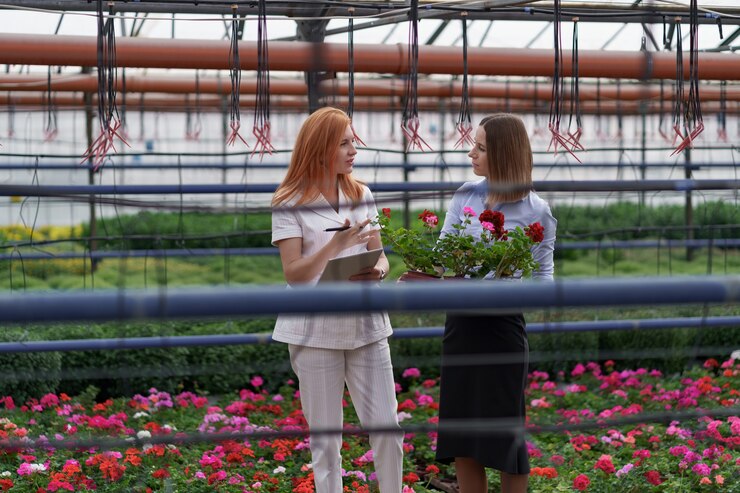 Kostenlose Foto gewächshausbesitzer präsentiert einem potenziellen kundenhändler blumenoptionen.