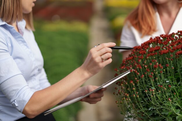 Gewächshausbesitzer präsentiert einem potenziellen Kundenhändler Blumenoptionen.