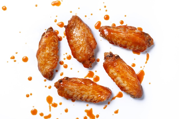 Gewürzte Hühnerflügel mit Cayennepfeffersauce auf weißem Hintergrund