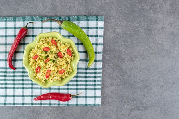 Gewürzter Reis mit in Scheiben geschnittenen Paprika in grüner Schüssel. Foto in hoher Qualität