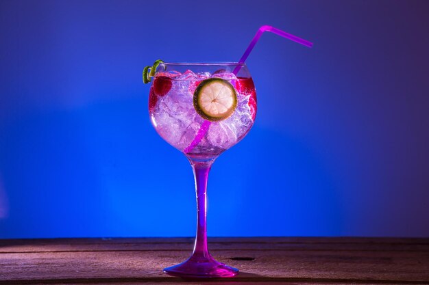 Gin Tonic mit Himbeeren und Kalk auf blauem Hintergrund