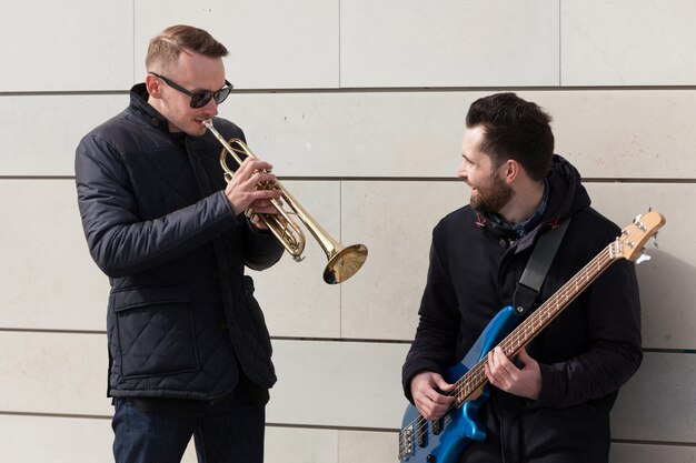 Gitarrist, der Trompetenspieler beobachtet, spielt sein Instrument