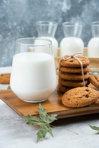 Gläser Milch mit Schokoladenkeksen und Blättern.