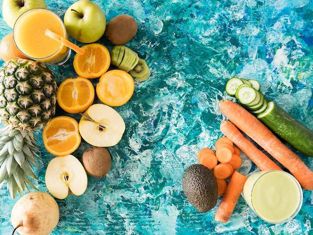 Gläser mit Detox-Saft neben Obst und Gemüse auf Holzuntergrund