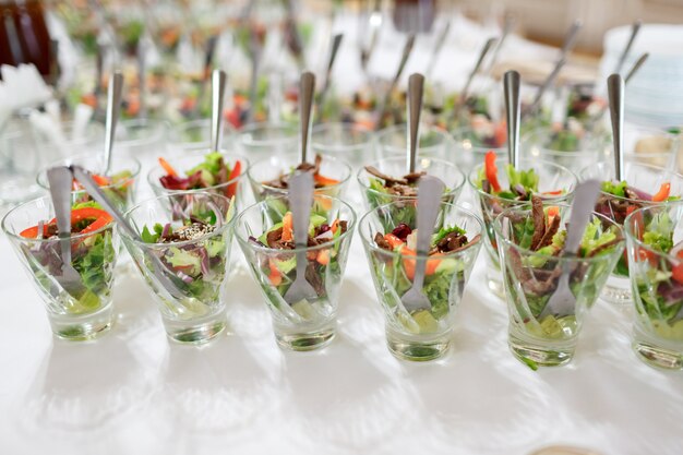 Gläser mit Salat auf weißem Tisch serviert