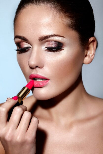 Glamour-Nahaufnahmeporträt des schönen Modells der jungen Frau der kaukasischen Brünette, das Make-up-Lippenstift auf ihren Lippen mit perfekter sauberer Haut anwendet