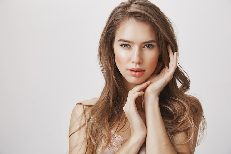 Kostenlose Foto glamour weibliche frau berührt das gesicht und schaut in die kamera