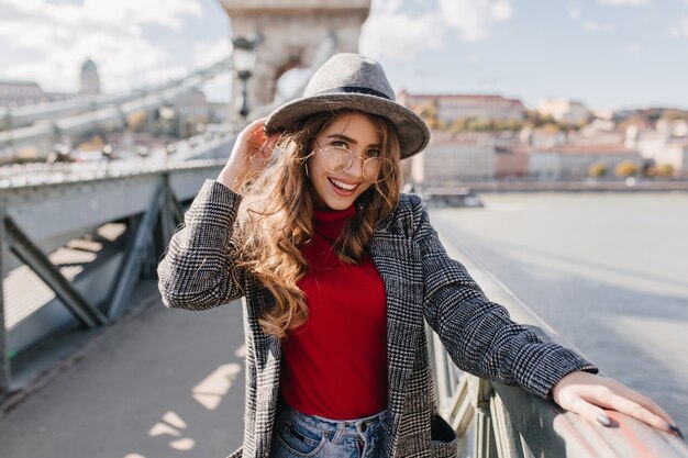 Glamouröses europäisches Mädchen im roten Pullover, der Freizeit draußen im sonnigen Herbsttag verbringt