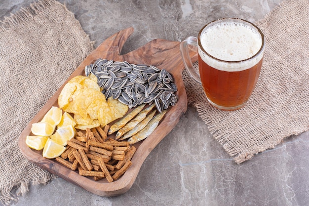 Glas Bier und Holzbrett mit Snacks. Foto in hoher Qualität