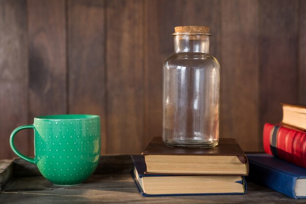 Glas, Bücher und Becher auf Holztisch