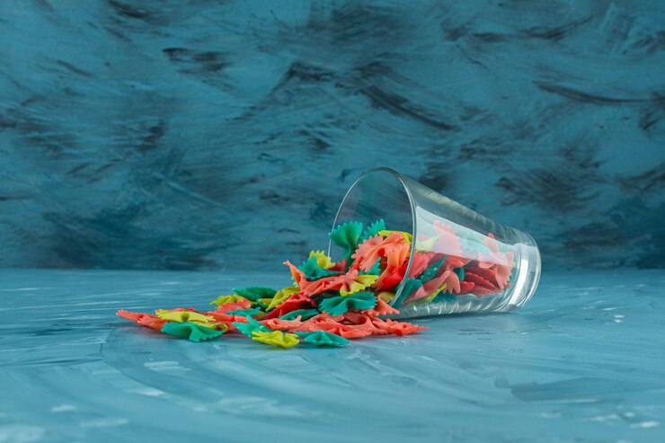 Kostenlose Foto glas der bunten rohen farfalle nudeln auf blauem hintergrund.