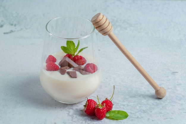 Glas erfrischender Himbeermilchshake zum Frühstück auf grauer Oberfläche.