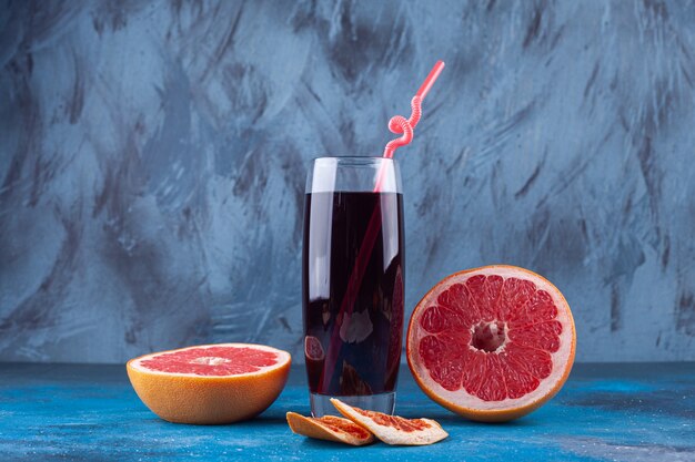 Glas frischen Saft mit geschnittener Grapefruit auf blauem Hintergrund.