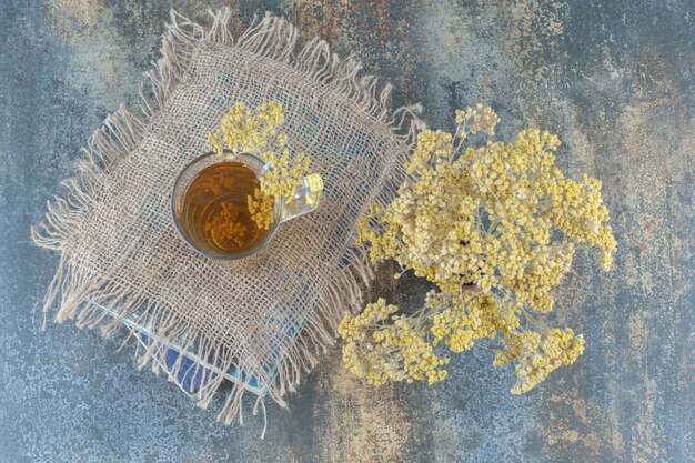 Glas grüner Tee und Blumen auf Buch.